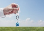 Hand holding key with a keychain in the shape of the house