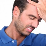 man holding his head with his hand, his face expresses failure